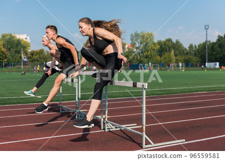 Two athlete woman and man runnner running hurdles 96559581