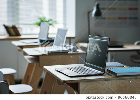 Computers with coding on screens standing on desks in class for studying IT technology 96560843