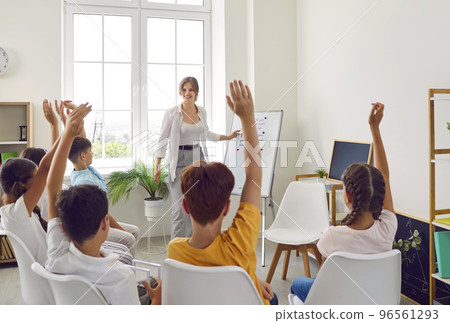Selective focus on hand. Children or Schoolkids or students raising hands up with teacher. 96561293