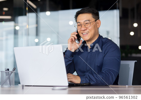 Successful Asian man smiling and talking on the phone, businessman in a shirt working inside the office using a laptop. 96561302