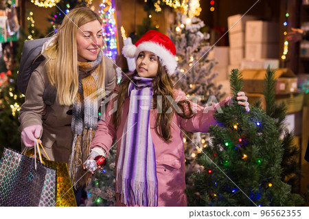 Family of mother and teen daughter having fun on outdoor fair, choosing fir tree for New Year celebration 96562355