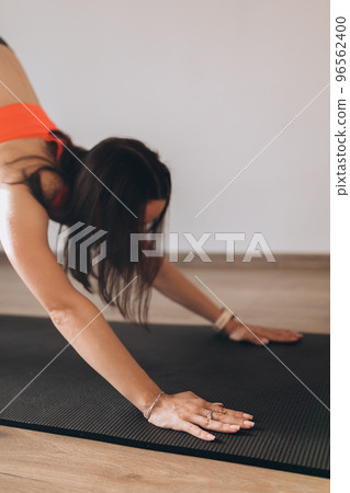 Young attractive woman practicing yoga, doing Downward facing dog exercise, adho mukha svanasana pose. Workout sport concept. 96562400