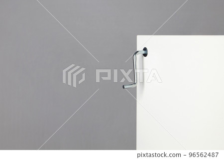 Screwing a metal confirmation into a white furniture board 96562487