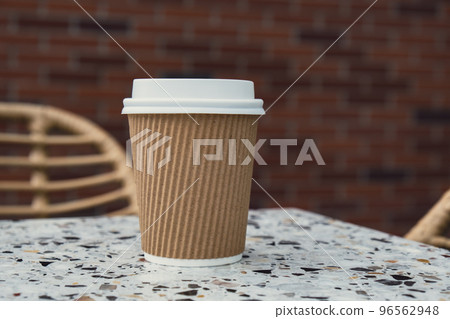 Eco recycling paper cup with coffee or tea on craft paper on table in beach cafe. Take away coffee to go. Copy space for text. Disposable 96562948