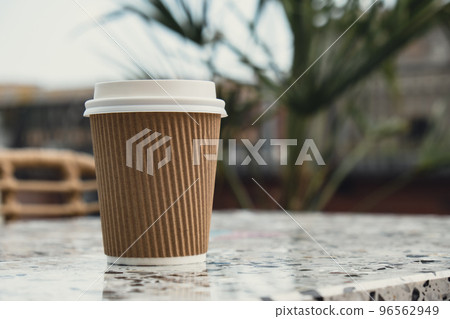 Eco recycling paper cup with coffee or tea on craft paper on table in beach cafe. Take away coffee to go. Copy space for text. Disposable Eco recycling paper cup with coffee or tea on craft paper on table in beach cafe. Take away coffee to go. Copy space for text. Disposable 96562949