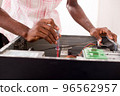 a computer expert repairs a computer 96562957