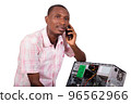 Young technician leaning against a broken computer 96562966