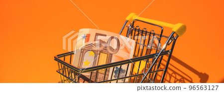 Euro paper currency 50 banknote money Shopping trolley cart on colorful orange yellow background. Copy space for your text. Online shopping, buy mall market shop consumer concept. Small toy Euro paper currency 50 banknote money Shopping trolley cart on colorful orange yellow background. Copy space for your text. Online shopping, buy mall market shop consumer concept. Small toy 96563127