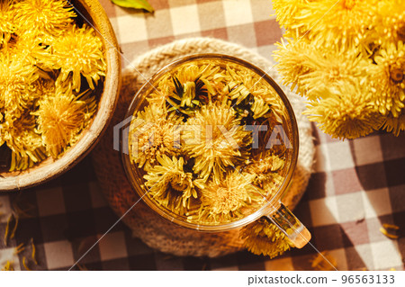 Dandelion flower healthy tea in glass cup on table. Herbal medicine Delicious tisane tea from with fresh yellow blossom dandelion flowers inside tea cup. Green clearing infusion Wildflowers Eco Dandelion flower healthy tea in glass cup on table. Herbal medicine Delicious tisane tea from with fresh yellow blossom dandelion flowers inside tea cup. Green clearing infusion Wildflowers Eco 96563133