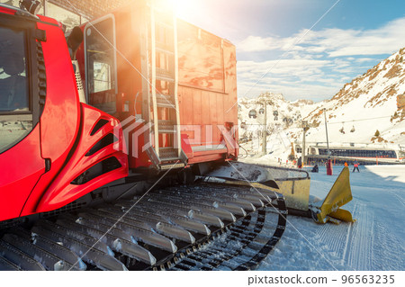 Red modern snowcat ratrack with snowplow snow grooming machine preparing ski slope piste hill at alpine skiing winter resort Ischgl in Austria. Heavy machinery mountain equipment track vehicle Red modern snowcat ratrack with snowplow snow grooming machine preparing ski slope piste hill at alpine skiing winter resort Ischgl in Austria. Heavy machinery mountain equipment track vehicle 96563235