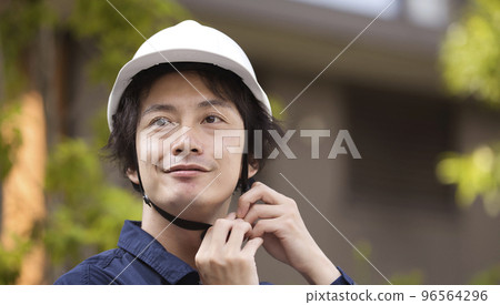 A man in work clothes wearing a helmet 96564296