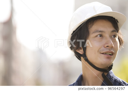A man in work clothes wearing a helmet 96564297