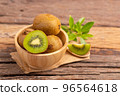 A half of kiwi in a wood bowl on the table 96564618