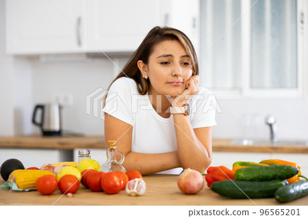 Sad woman looking at vegetable at kitchen, dieting problems 96565201