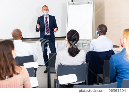 caucasian male businessman in mask gives advice to manager in meet room 96565204