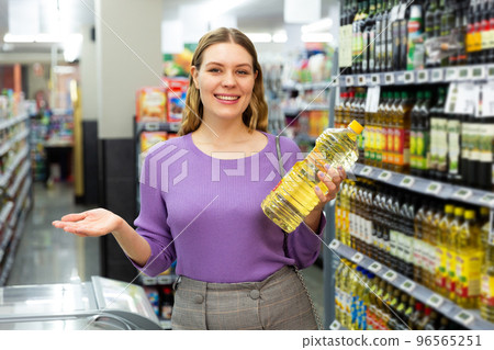 Smiling young woman choosing the different oil in the modern supermarket 96565251