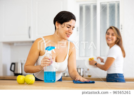 Two young women cleaning the kitchen and washing dishes 96565261