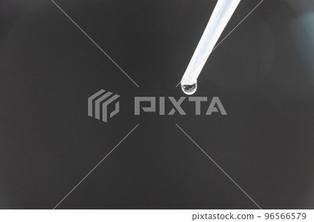 Water droplets dripping from the tip of the dropper 96566579