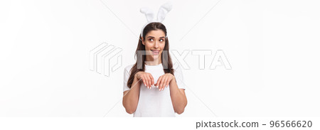 Funny and silly, playful girl in rabbit ears, t-shirt, looking away and licking lips, daydreaming about something delicious on Easter day, imitating bunny with hands pulled close to chest like paws Funny and silly, playful girl in rabbit ears, t-shirt, looking away and licking lips, daydreaming about something delicious on Easter day, imitating bunny with hands pulled close to chest like paws 96566620