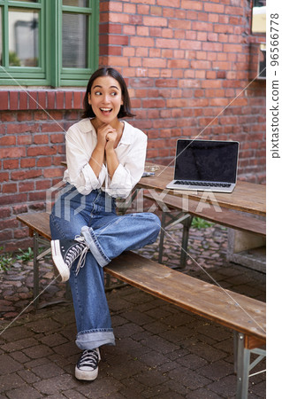 Beautiful asian woman with laptop, sitting and working in cafe, laughing and smiling, drinking coffee Beautiful asian woman with laptop, sitting and working in cafe, laughing and smiling, drinking coffee 96566778