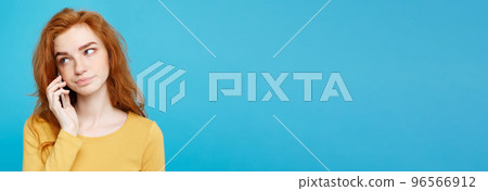 Lifestyle and Technology concept - Portrait of ginger red hair girl with shocking and stressful expression while talking with friend by mobile phone. Isolated on Blue Pastel Background. Copy space. 96566912