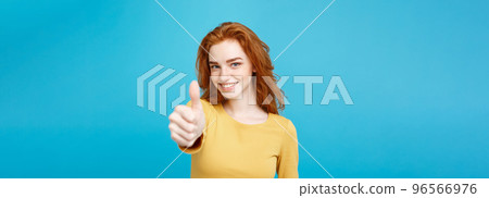 Portrait of young stylish freckled girl laughing with showing thumps up at camera. Copy space. Portrait of young stylish freckled girl laughing with showing thumps up at camera. Copy space. 96566976
