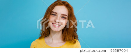 Headshot Portrait of happy ginger red hair girl with freckles smiling looking at camera. Pastel blue background. Copy Space Headshot Portrait of happy ginger red hair girl with freckles smiling looking at camera. Pastel blue background. Copy Space 96567004