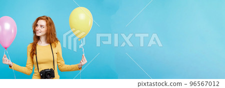 Lifestyle and Party concept - Close up Portrait young beautiful attractive ginger red hair girl with colorful balloon and vintage camera. Blue Pastel Background. Copy space. Lifestyle and Party concept - Close up Portrait young beautiful attractive ginger red hair girl with colorful balloon and vintage camera. Blue Pastel Background. Copy space. 96567012