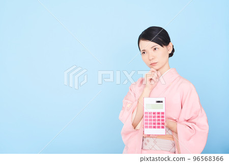 一個穿著和服的女人拿著計算器 96568366