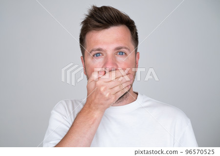 Keeping your secret. man covering mouth with hand and looking at camera. 96570525