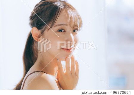 Photo of a young woman doing skin care in the morning sun 96570694