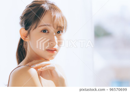 Photo of a young woman doing skin care in the morning sun 96570699