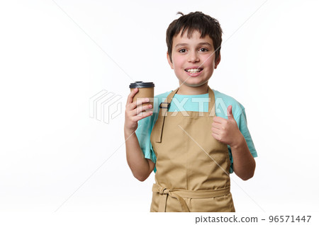 Isolated portrait on white background of a happy teenage boy bartender showing thumb up, selling a takeaway coffee beverage drink in cardboard mug. Hot beverage to go. Copy space for your advertising Isolated portrait on white background of a happy teenage boy bartender showing thumb up, selling a takeaway coffee beverage drink in cardboard mug. Hot beverage to go. Copy space for your advertising 96571447