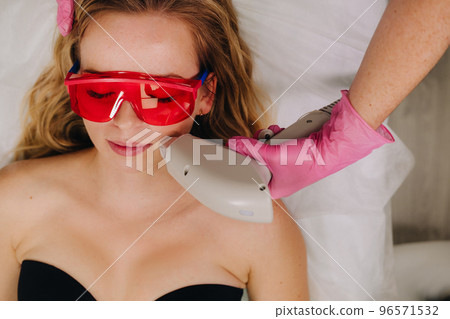 A girl in black underwear gets laser hair removal on her body in the salon 96571532