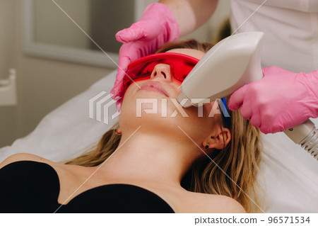 A girl in black underwear gets laser hair removal on her body in the salon 96571534