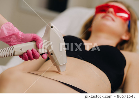 A girl in black underwear gets laser hair removal on her body in the salon 96571545