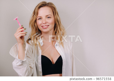 A beautiful portrait of a feminine woman in a shirt and underwear with a pink razor in her hand A beautiful portrait of a feminine woman in a shirt and underwear with a pink razor in her hand 96571558
