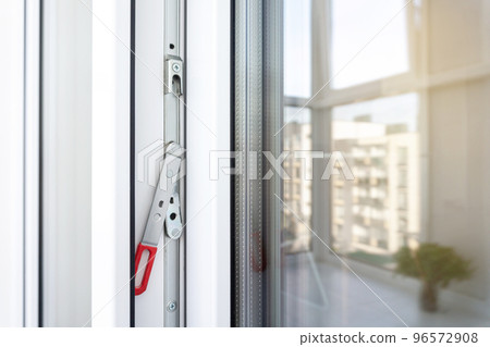 White plastic balcony door frame with fittings. Concealed drive lever close-up. Upvc windows and doors accessories and hardware. 96572908