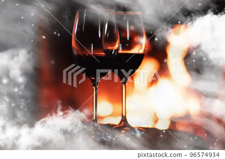 Winter atmosphere and Christmas holiday time, wine glasses in front of fireplace covered with snowy effect on window glass, holidays backgrounds Winter atmosphere and Christmas holiday time, wine glasses in front of fireplace covered with snowy effect on window glass, holidays backgrounds 96574934