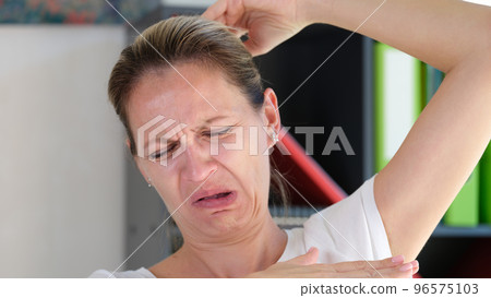 Female sniffing armpits and feeling of revulsion because of smell 96575103