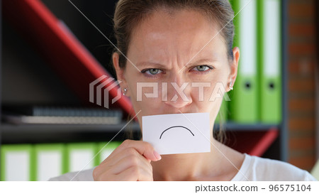 Grumpy woman covering face with paper unhappy emoticon symbol 96575104