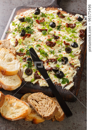 Homemade Trendy Butter Board with Herbs, olives, sun-dried tomatoes and Bread closeup. Vertical 96575496