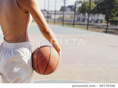 Stylish cool teen girl gathering at basketball court, playing basketball outdoors Stylish cool teen girl gathering at basketball court, playing basketball outdoors 96576486