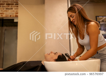 Cheerful young brunette womn enjoying head massage and washing hair 96576997