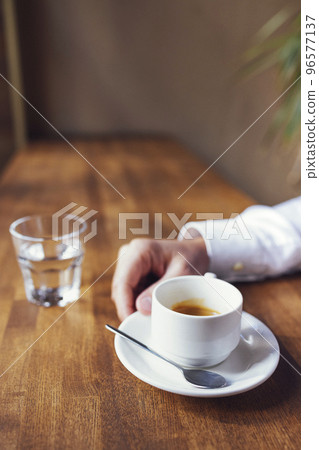 Male hand holds white cup of espresso coffee. Closeup photo with selective focus 96577137
