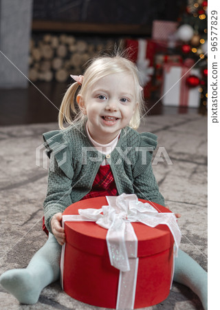 Portrait of little blonde girl opening Xmas presents. Desired present. Amazed little child with Christmas gift 96577829