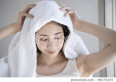 Young woman wiping her hair with a towel 96578255