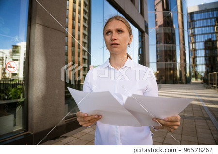 Business woman with papers in hand against the background of the office center Business woman with papers in hand against the background of the office center 96578262