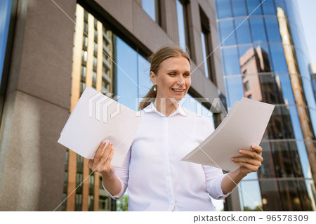 Business woman with papers in hand against the background of the office center Business woman with papers in hand against the background of the office center 96578309