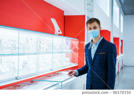 young man in a jewelry store in a jacket and a medical mask 96578350